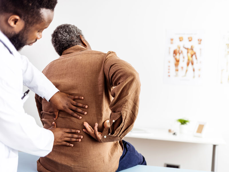 Male orthopedist examining patient's back in clinic